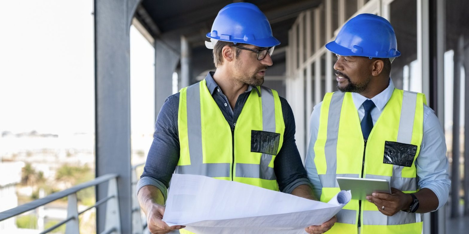 Two contractors reviewing building plans on site