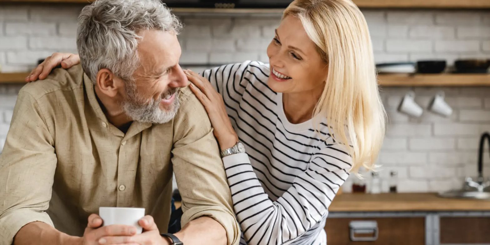A couple sharing coffee and a laugh in their kitchen